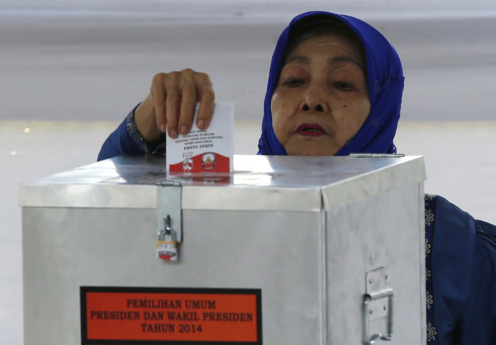 A voter casts ballot at polling station, where Indonesian presidential candidate Joko